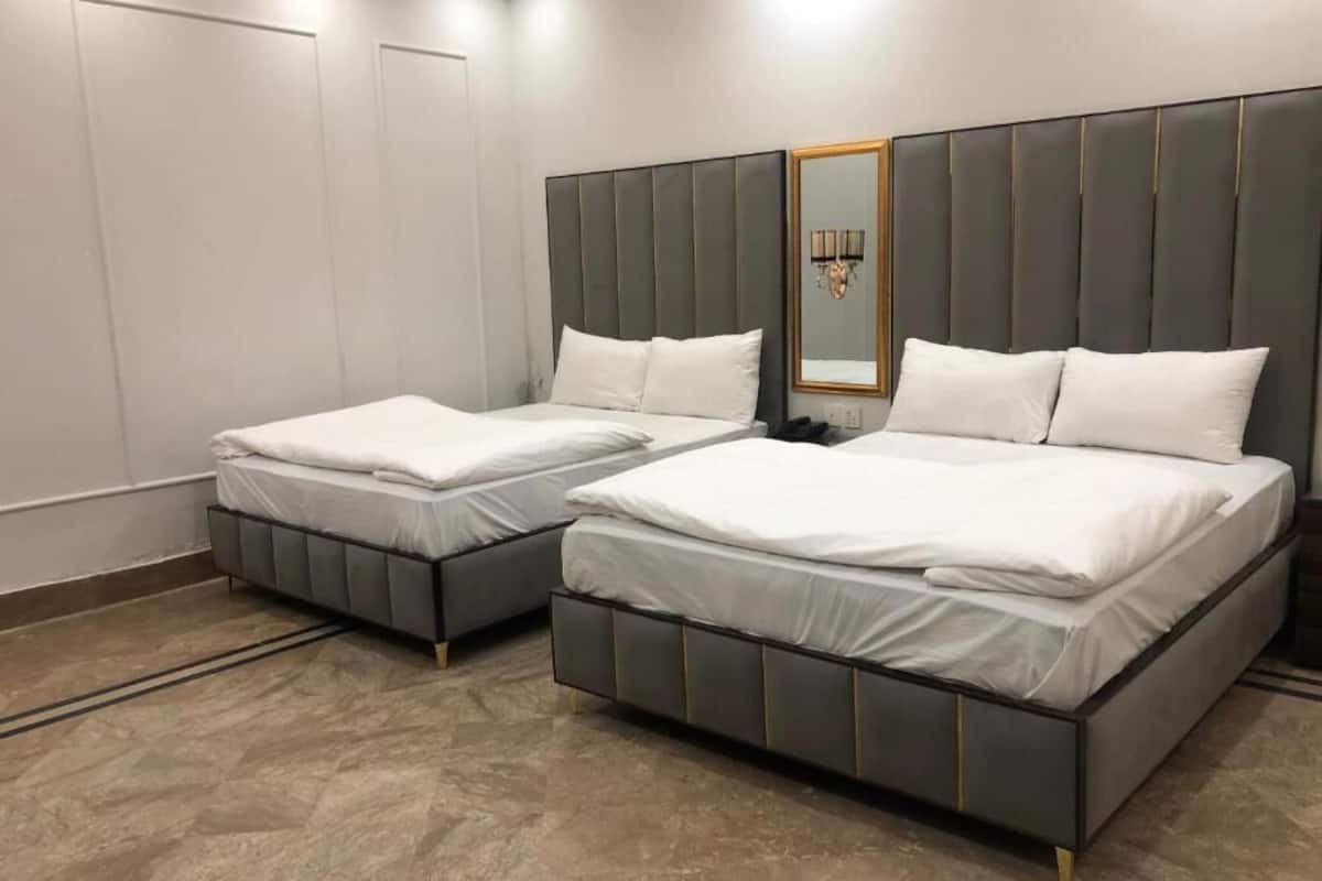 A hotel room with two beds, a large mirror, and a chandelier.