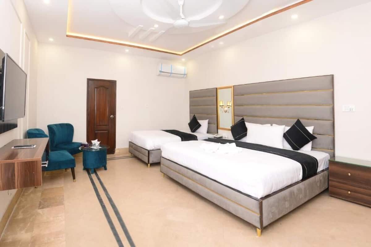 A modern hotel room with a large bed, a desk, a chair, and a television.