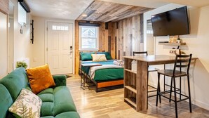 Une pièce confortable avec un lit, un bureau, une télévision et un canapé vert.