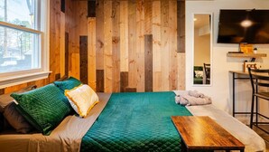 Une pièce comprenant un lit, un panneau mural en bois, un téléviseur et une petite table.
