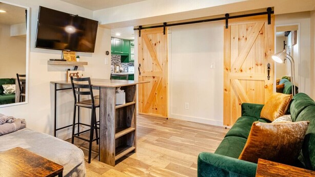 Un salon moderne avec un canapé vert, une table basse en bois et un coin repas doté d’un bar.