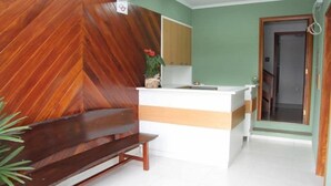 A reception area with a wooden bench, a reception desk, and a mirror. - Hotel Ricci  (Batatais)