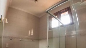 A modern bathroom with a glass shower enclosure, a marble sink, and a toilet. - Hotel Ricci  (Batatais)