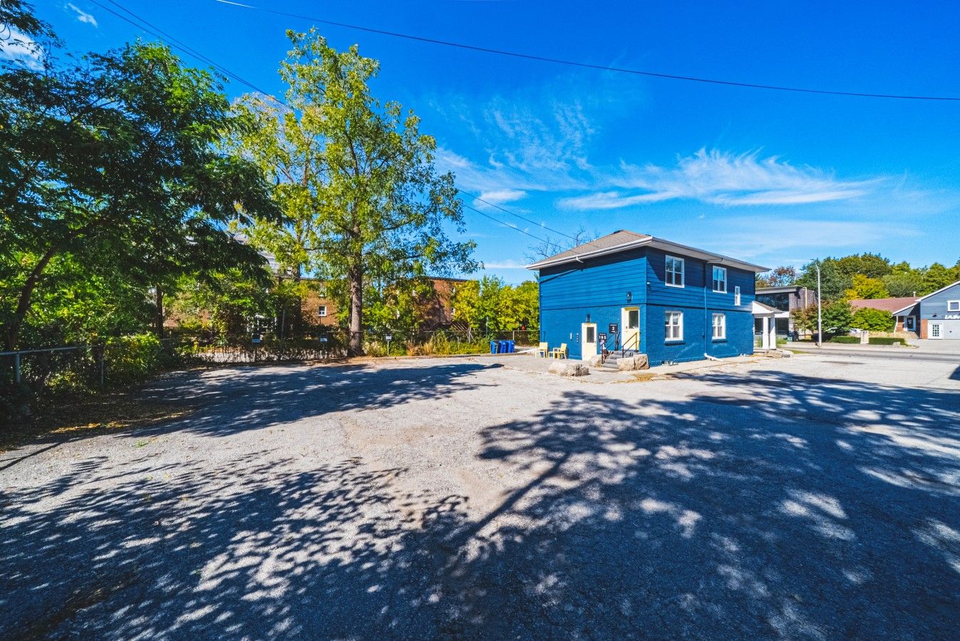 A blue building with a flat roof, a front porch, and a driveway leading to a parking area.