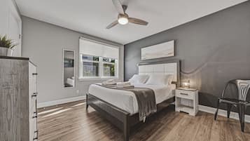 Une chambre à coucher comprenant un lit, une table de chevet, une chaise et un ventilateur de plafond.