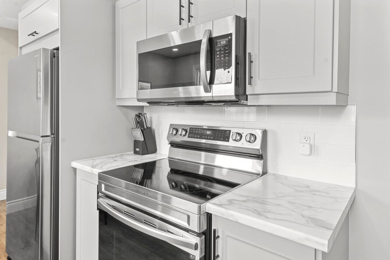 Una cucina moderna con elettrodomestici in acciaio inossidabile, tra cui un forno a microonde, forno e frigorifero.