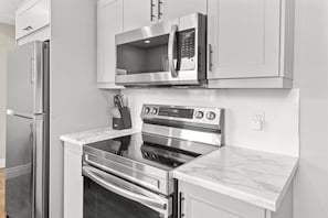 Una cucina moderna con elettrodomestici in acciaio inossidabile, tra cui un forno a microonde, forno e frigorifero.