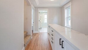 A narrow hallway with wooden flooring, white walls, and a white countertop with drawers. - Hot Tub, Newly Updated, Near DT, Free parking | TS (Peterborough)