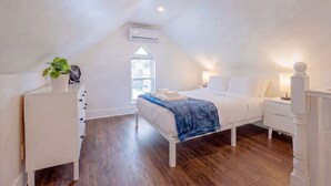A bedroom with a sloped ceiling, a bed, a bedside table, a nightstand, a dresser, and a window. - Hot Tub, Newly Updated, Near DT, Free parking | TS (Peterborough)