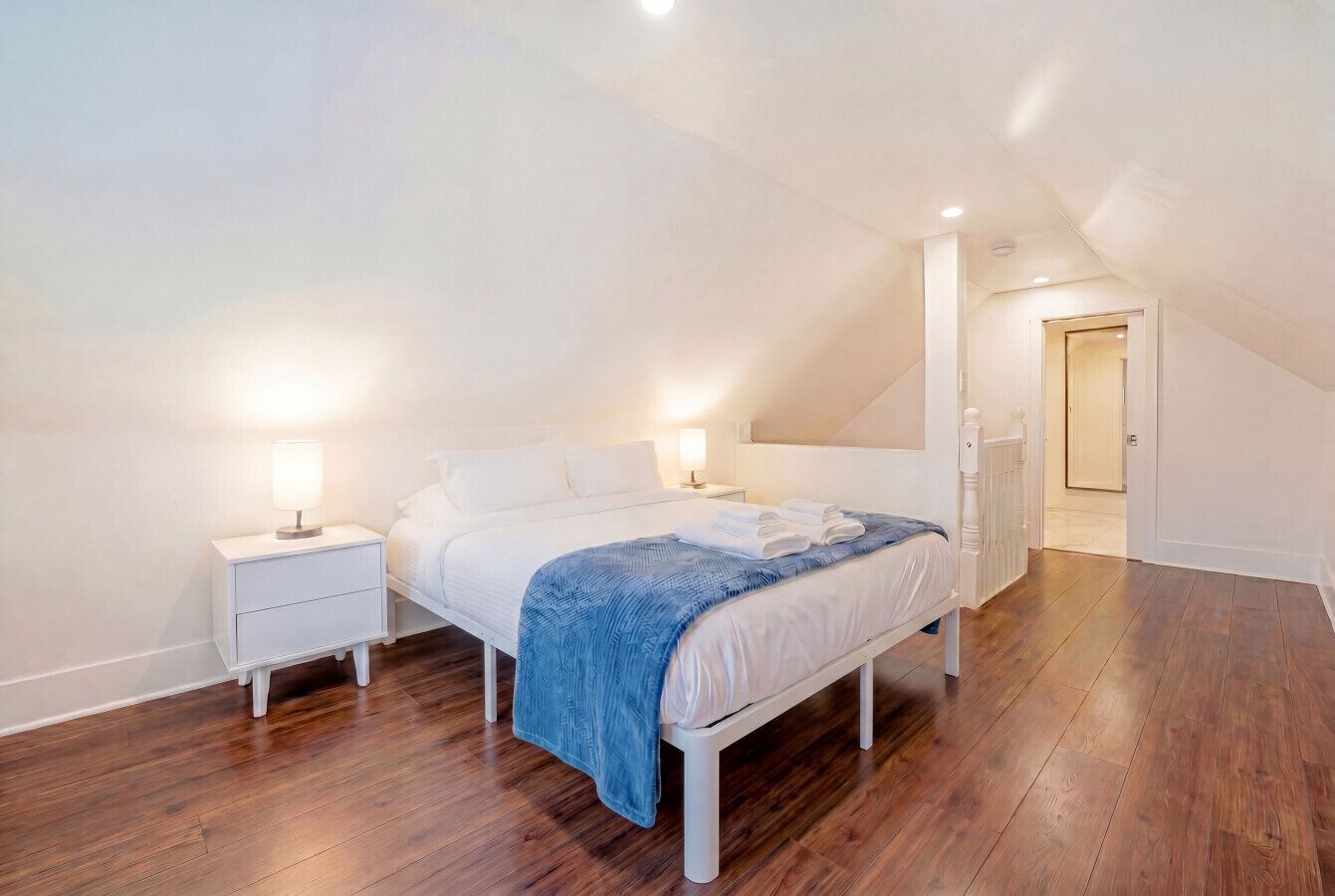 A bedroom with a bed, nightstands, and a walk-in closet.