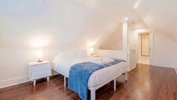 A bedroom with a bed, nightstands, and a walk-in closet.