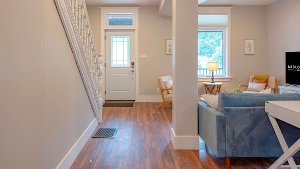 A modern living room with a grey sofa, a TV, and a small table. - Hot Tub, Newly Updated, Near DT, Free parking | TS (Peterborough)