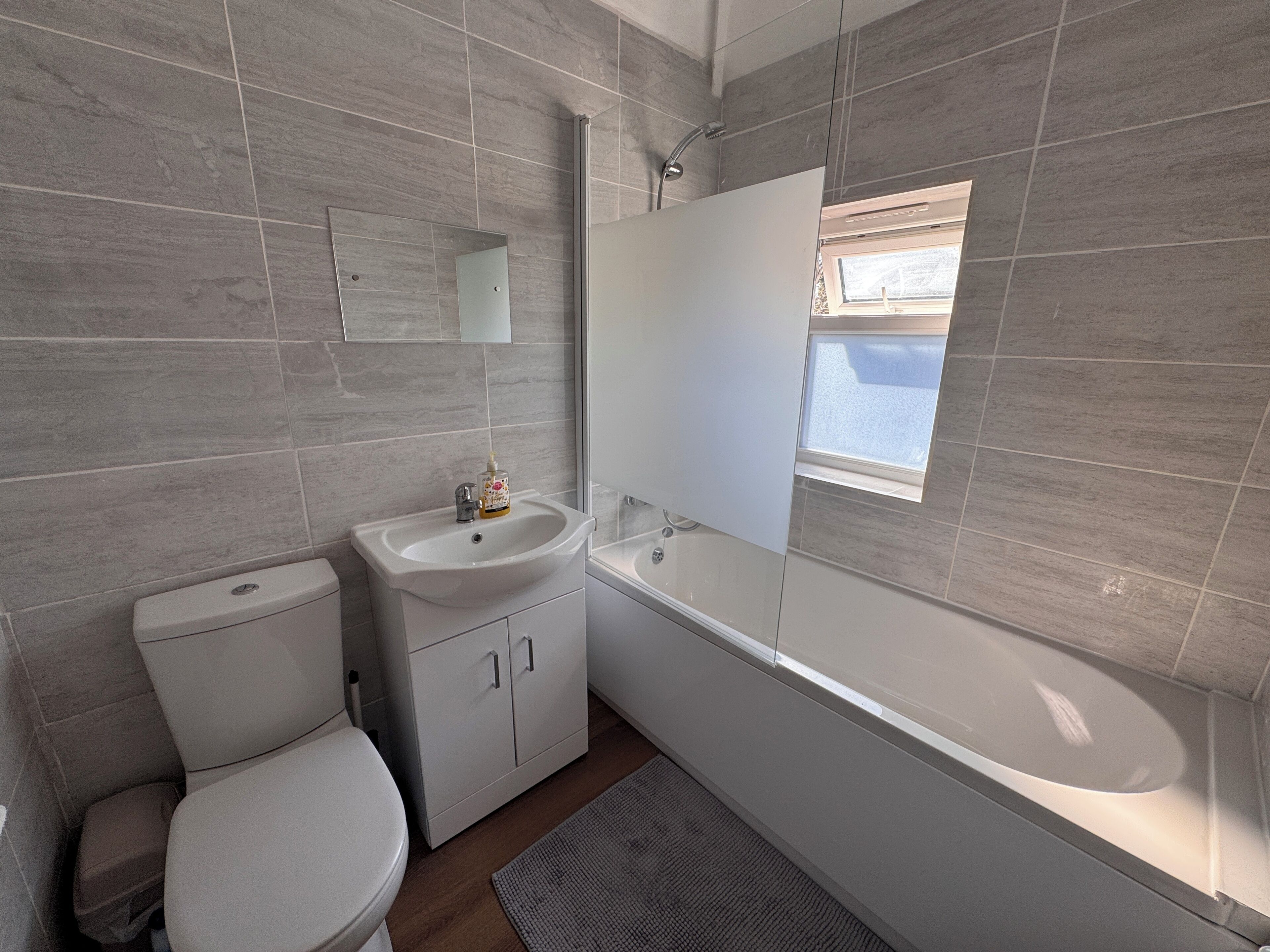 A modern bathroom with a toilet, sink, and bathtub.