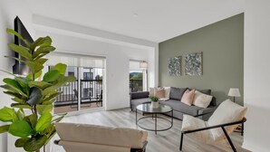 A modern living room with a sofa, armchair, coffee table, and a large plant. - Modern Gem, Spacious, Parking | THH (Ajax)