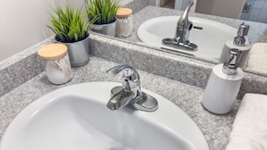 A bathroom sink with a modern faucet, a mirror, and a granite countertop. - Downtown, 2 Bedroom, Parking | TJS3 (Burlington)