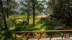 A deck with a view of a grassy area, a fire pit, and outdoor furniture. - Swimming, Fishing, Firepit, Amazing Views! (Brainerd)