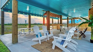 An outdoor patio with Adirondack chairs, a picnic table, and a view of the horizon. - Two Port A Homes Near Beach & Nature Preserve Ideal Group Retreat (Port Aransas)
