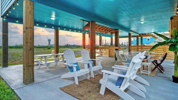 An outdoor patio with Adirondack chairs, a picnic table, and a view of the horizon.