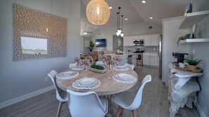 A modern kitchen with white cabinetry, a dining area with a round table, and a decorative wall piece.