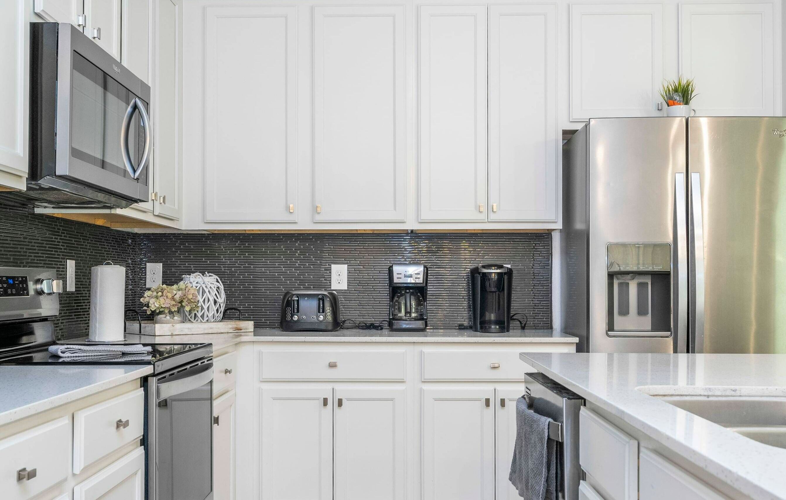 A modern kitchen with white cabinets, stainless steel appliances, a coffee maker, and a toaster.