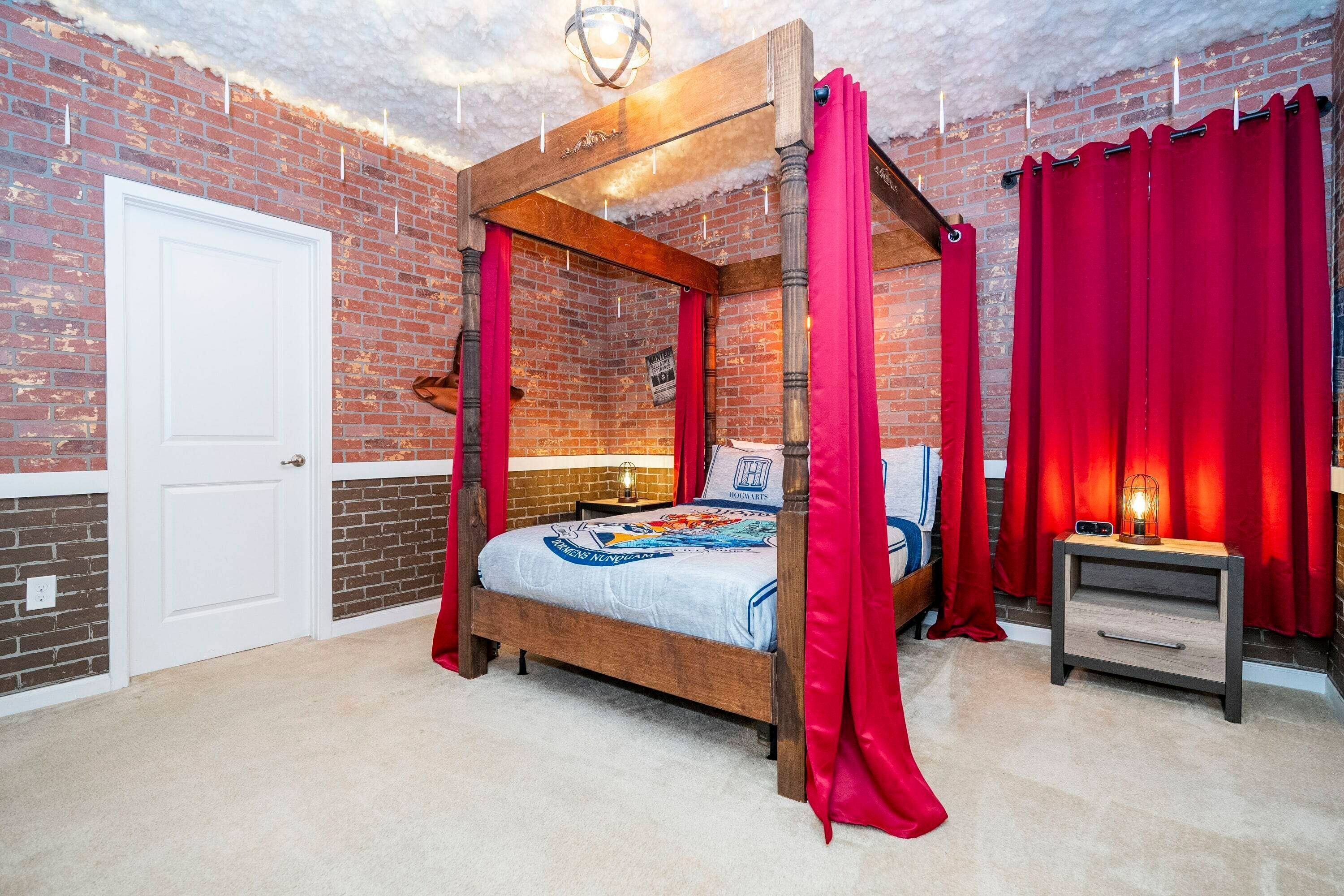 A four-poster bed with a canopy, a bedside table with a lamp, and a brick wall with a white door.