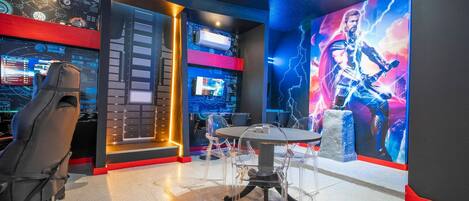 A gaming room with a large screen, multiple monitors, and a gaming chair.