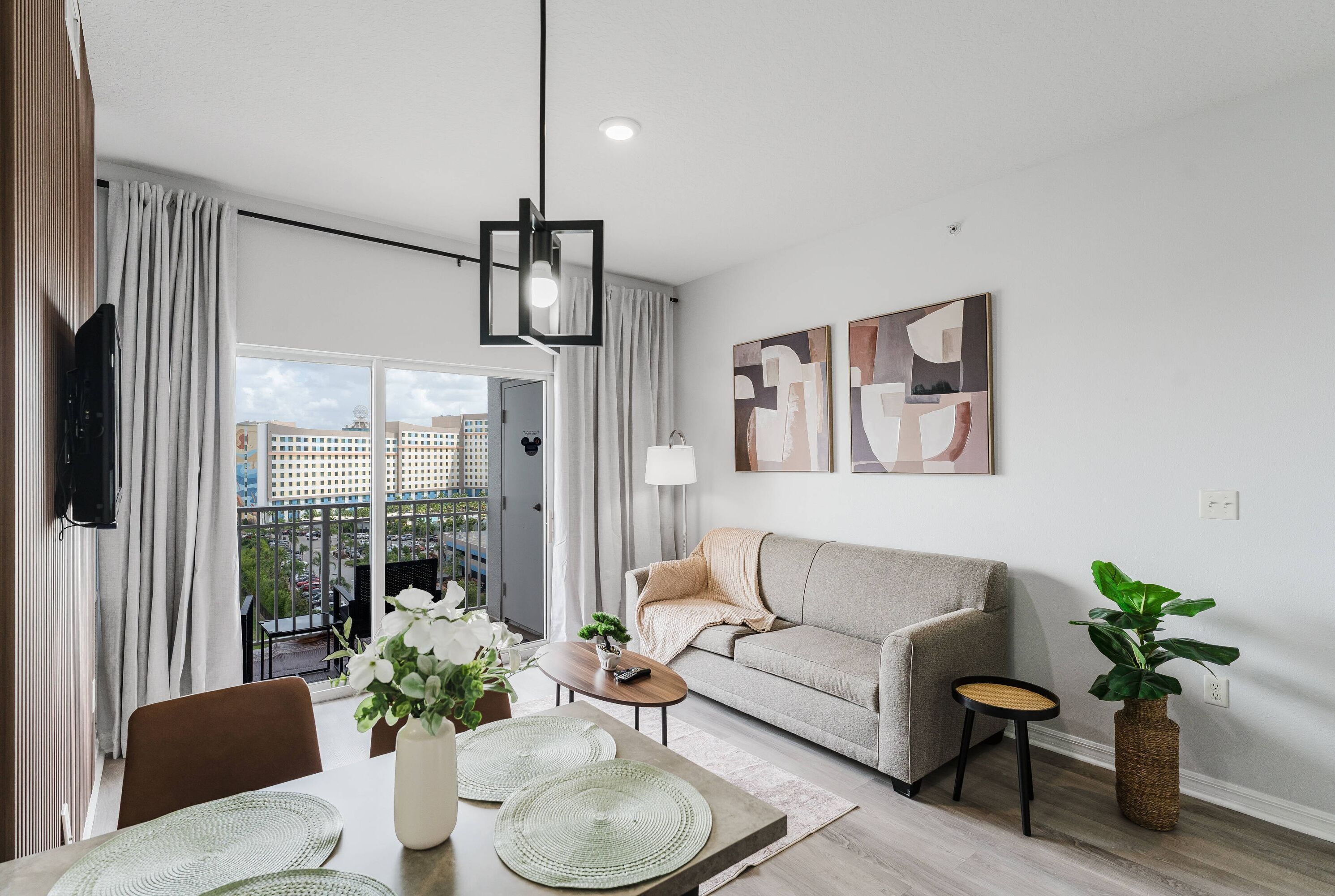 Un salon moderne avec un canapé, une table à manger avec des sets de table, une petite table d’appoint et une plante en pot.