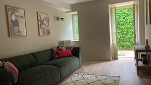 Ein Wohnzimmer mit einem grünen Sofa, einem gemusterten Teppich und zwei Wandleuchten.