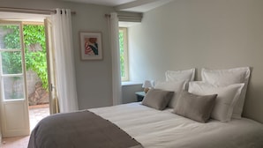 Ein Schlafzimmer mit einem großen Bett, einem Fenster mit Vorhängen und einem gerahmten Bild an der Wand.