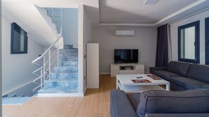A modern living room with a staircase, a flat-screen TV, a grey sofa, and a white coffee table. - modu’s semi-detached houses (marmaris)