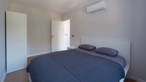A bedroom with a bed, a nightstand, a white wardrobe, and an air conditioning unit. - modu’s semi-detached houses (marmaris)