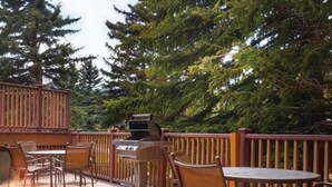 An outdoor deck with wooden furniture, a fire pit, and a grill.