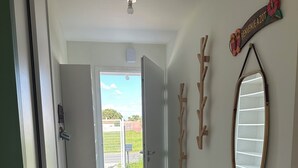 En hall med ett klinkergolv, en dörr som leder ut och en spegel som är monterad på väggen.