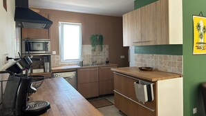 A modern kitchen with wooden cabinets, a built-in microwave, and a large window.