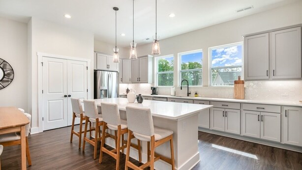 A modern kitchen with a large island, bar stools, white cabinets, and pendant lighting. - UNCC 4BR | Pet-Friendly Stay (Charlotte)