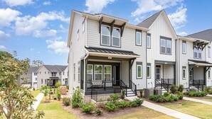 A multi-story residential building with a front porch, a small garden, and a clear sky. - UNCC 4BR | Pet-Friendly Stay (Charlotte)