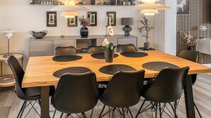 A modern dining area with a wooden table, black chairs, and pendant lighting.
