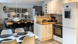 A modern kitchen with a dining area, featuring a refrigerator, oven, and various kitchen appliances.