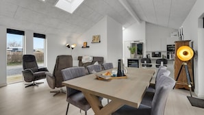 A spacious living area with a high ceiling, a dining table, and modern furniture.