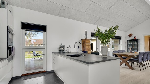 A modern kitchen with a large island, built-in appliances, and a dining area with a table and chairs.