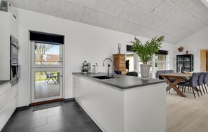 Una cucina moderna con un'isola grande, elettrodomestici integrati e un'area pranzo con tavolo e sedie.