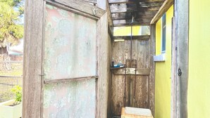 A narrow wooden structure with a bench, a small table, and a door.