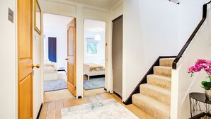 A hallway with a carpet, wooden door, and a staircase with a handrail.