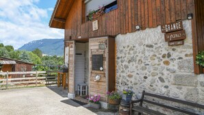 Un edificio rústico de madera con fachada de piedra, un balcón de madera adornado con flores y un letrero que indica que es un hotel.