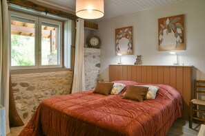Une chambre à coucher avec un lit, une tête de lit en bois, une horloge murale et une fenêtre avec des rideaux.