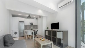 A modern living space with a sofa, a dining table, a TV, and a kitchen area. - Apartment 'Room 3' with Wi-Fi and Air Conditioning (Torremolinos)