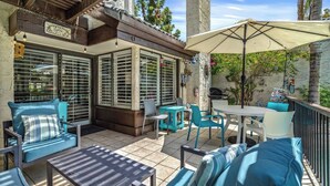 A patio area with outdoor seating, including chairs and tables, and a covered section with a grill.