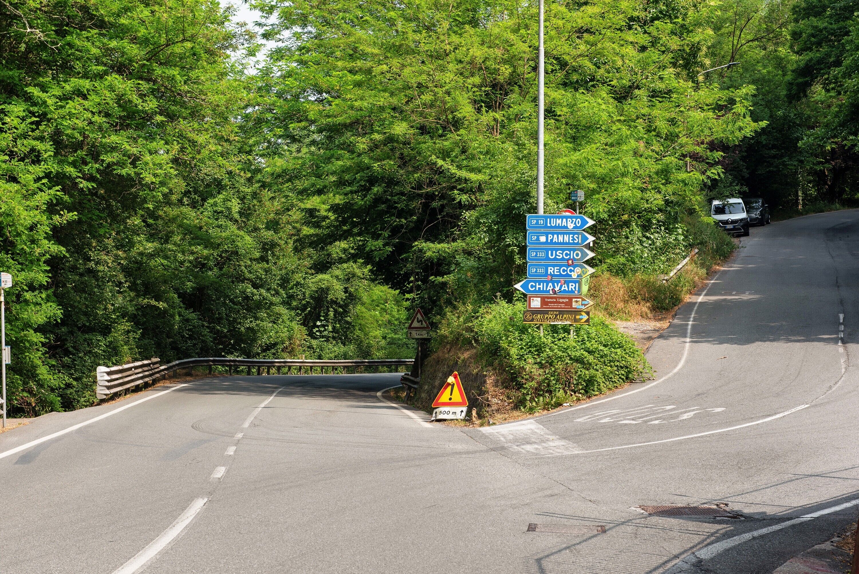 A road with directional signs and a guardrail.