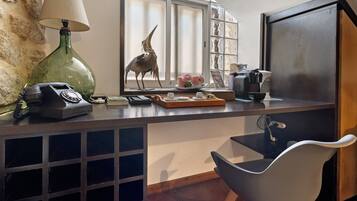 A kitchen with a green lamp, a telephone, a decorative bird, a coffee maker, and a window with a view.