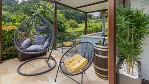 A balcony with two hanging chairs, a barrel, and a potted plant. - Holiday Home 'Cevidade' with Lake View, Wi-Fi and Air Conditioning (Melgaço)